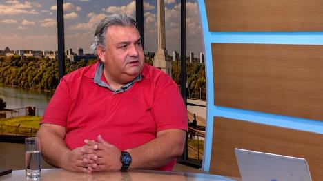Čovek sede kose, u crvenoj majici, u televizijskom studiju