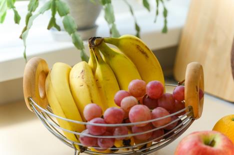 metalna kopa sa drvenim drškama sa grožđem i bananama na stolu