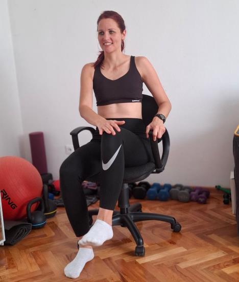 trener sedi u stolici, leva noga je podignuta od poda u visini kukova a desna šaka je položena na levo koleno