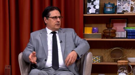 Čovek sa naočarima u sivoj fotelji