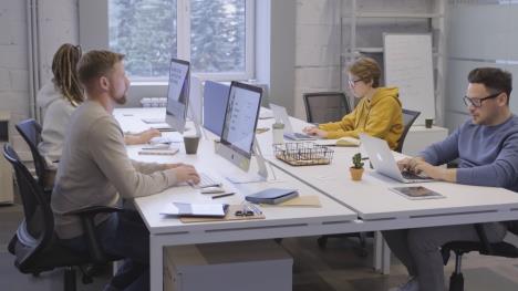 Ljudi za belim stolom na kompjuterima