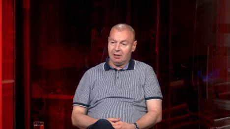 Čovek sedi, iza njega crvena pozadina