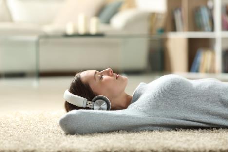 devojka leži na tepihu, sluša muziku i opušta se