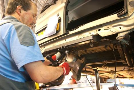 automehaničar skida kuku za vuču sa automobila