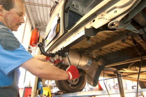 automehaničar skida kuku za vuču sa automobila