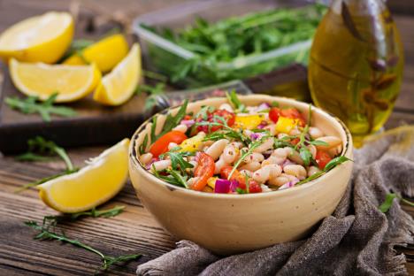 salata od pasulja u drvenoj činiji na stolu sa kriškama limuna