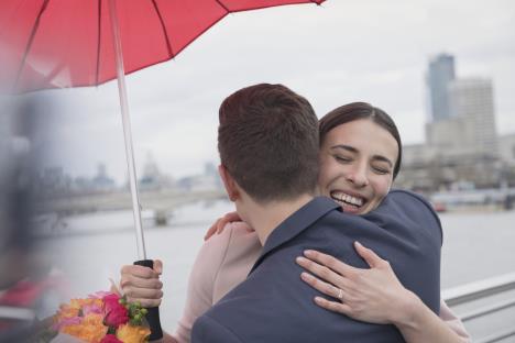 Momak i devojka se grle pod kišobranom