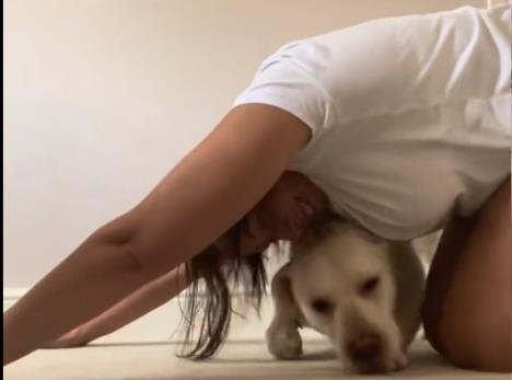 Devojka se isteže na podu, a pas je ometa.jpg