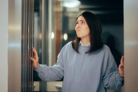 devojka u sivom duksu stoji na vratima lista sa zabrinutim izrazom lica
