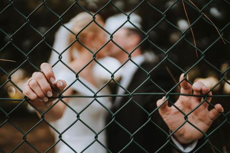 Mlada i mladoženja se ljube i drže za žičanu ogradu