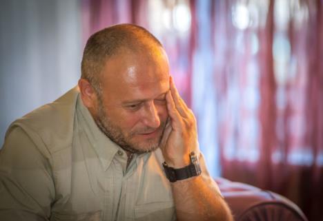 Muškarac gleda u pod i drži ruku na licu