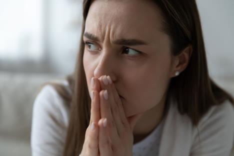 Namrštena žena drži sklopljene ruke na ustima
