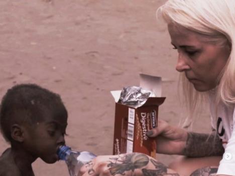 Anja dečaku iz Nigerije daje da pije vode iz flašice.jpg