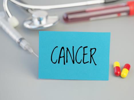 Na stolu je tablica sa oznakom CANCER, pored su dve pilule vakcina i test krvi