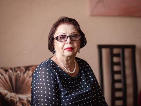 Starija žena sa naočarima sedi na krevetu