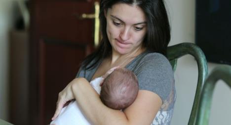 Žena sedi na stolici i drži dete u naručju