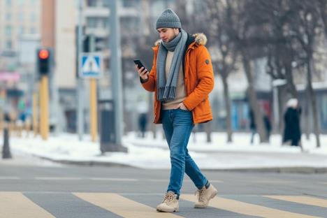 Tinejdžer drži telefomn u rukama i hoda ulicom