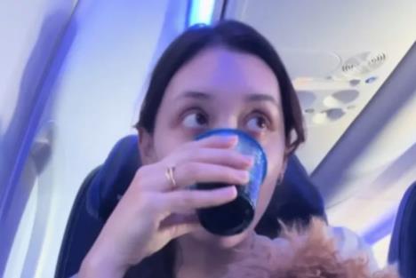 Devojka u avionu pije kafu.jpg