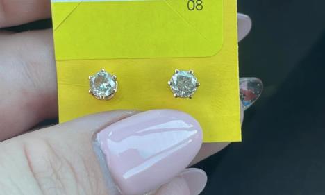 Ženska ruka drži par minđuša.jpg