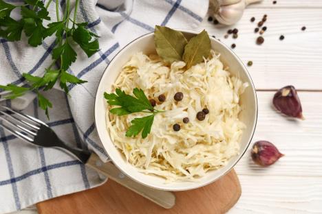 Kupus salata u keramičkoj posudi stoji na drvenoj dasci