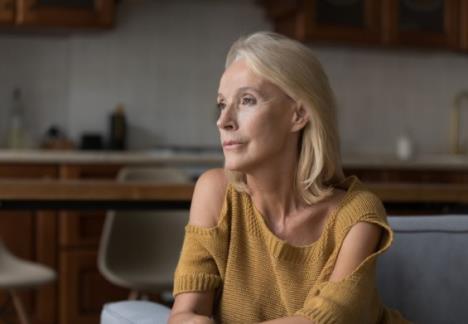 Žena u pletenoj majici golih ramena gleda u daljinu