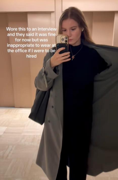 Žena u sivom kaputu i čizmama na štiklu stoji ispred ogledala spremna za razgovor za posao