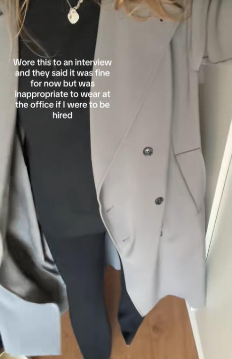 Žena u sivom kaputu i čizmama na štiklu stoji ispred ogledala spremna za razgovor za posao