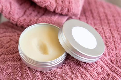 Domaći balzam za usne u metalnoj posudi sa sastojcima – pčelinjim voskom, ši maslacem i kokosovim uljem