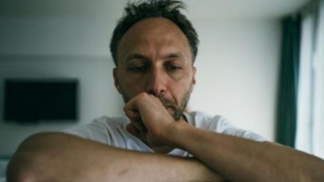 Muškarac sa šakom na usnama gleda zamišljeno.jpg