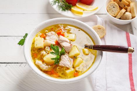 Pileća supa u belim tanjirima servirana na stolu