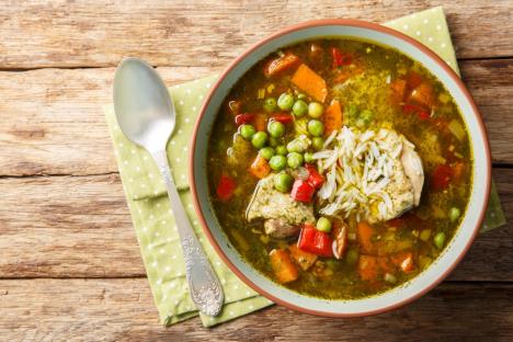 tanjir čorbe od graška sa piletinom na drvenom stolu