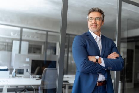 zadovoljan muškarac srednjih godina u teget odelu na radnom mestu