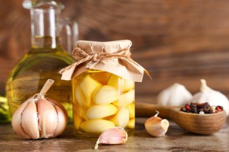 beli luk u teglici sa uljem i satojcima na drvenom stolu