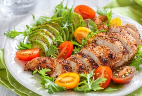 pečena ćuretina servirana na tanjiru sa avokadom, rukolom i čeri paradajzom