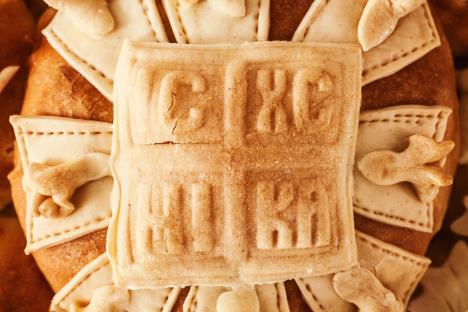 Okrugli slavski kolač ukrašen tradicionalnim simbolima i krstom, spreman za Aranđelovdan