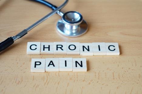 ispis hroničan bol na malim belim pločicama složenim na drvenom stolu pored stetoskopa