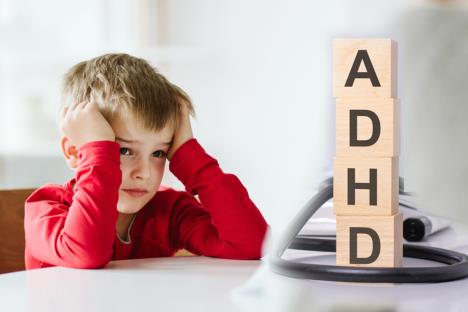 dečak sa crvenom majicom sedi za stolom/ADHD