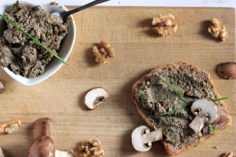 posna pašteta od pečuraka i oraha premazana preko hleba servirana na drvenoj dasci sa listićima pečuraka i orasima