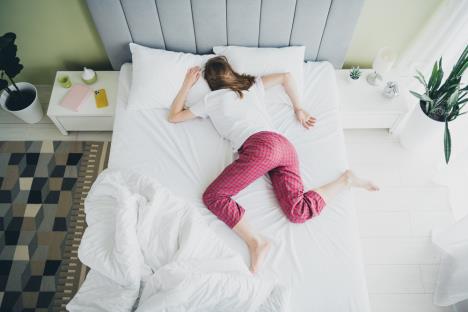 mlada žena u crvenoj pidžami i beloj majici spava na stomaku