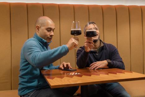 Dva muškarca u restoranu piju vino