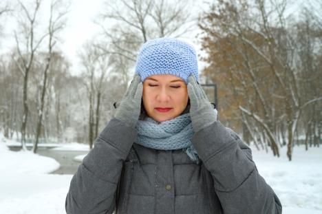 žena se drži za glavu oko nje je snežni pokrivač
