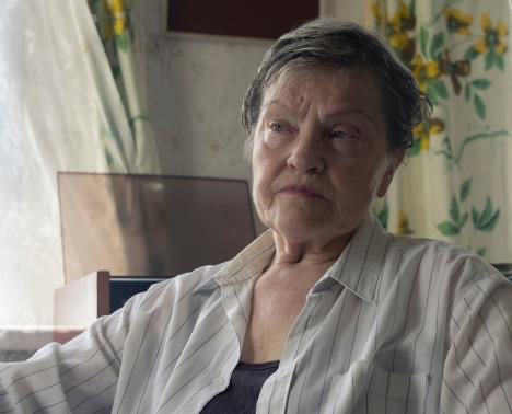 Starija žena sedi u kući ozbiljna lica