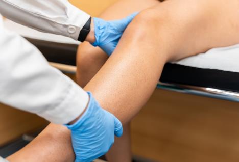 lekar sa plavim higijenskim rukavicama pregelda elvo koleno pacijentkinje