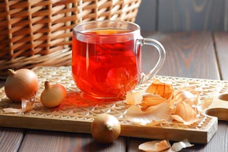 čaj od luka u providnoj čaši sa glavicama crnog luka