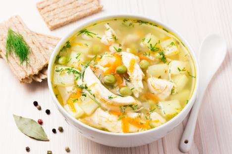 pileća supa sa povrćem servirana u belu činijicu pored koje je keramička bela kašika