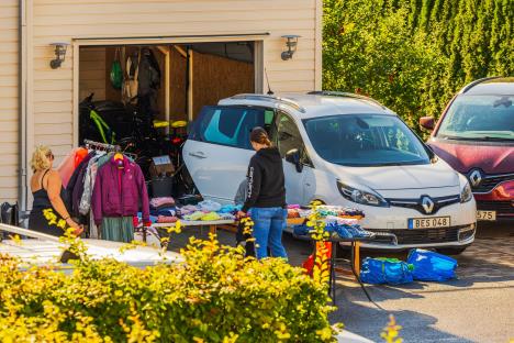 Žena u dvorištu među parkiranim kolima i gomilom stvari