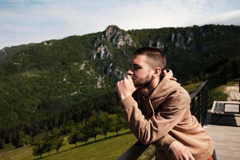 Mlad muškarac naslonjen na ogradu uživa u prizoru