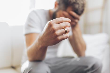 Muškarac slomljenog srca pokazuje venčani prsten, koncept kajanje nakon preljube