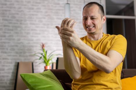 muškarac u žutoj majci levom, rukom drži desnu šaku koja boli