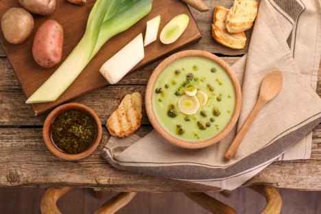 krem čorba od praziluka servirana u činiji uz prazilik sećen na kolutove i uz prepečen hleb